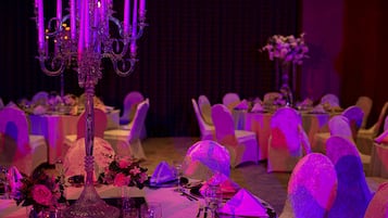 Ein Festsaal mit gedeckten Tischen für eine festliche Veranstaltung, mit Kerzenständern und floralen Tischdekorationen.