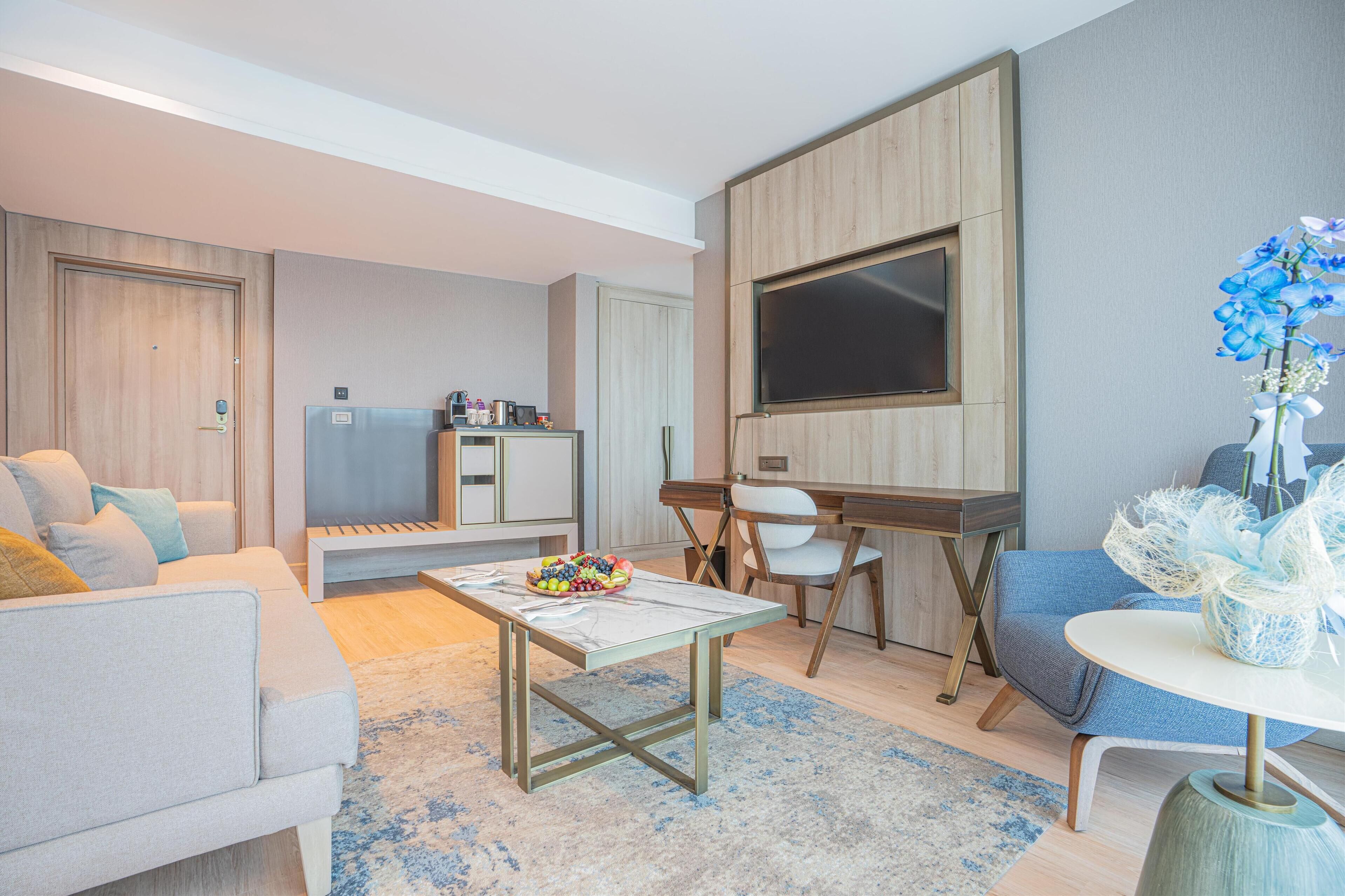 A modern living room with a sofa, coffee table, and a desk area.