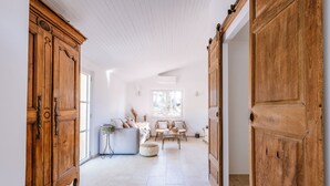 Una habitación amplia con un gran armario de madera, un sofá blanco y una mesita redonda.