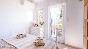 Un dormitorio con cama, mesita de noche, ventana y puerta.