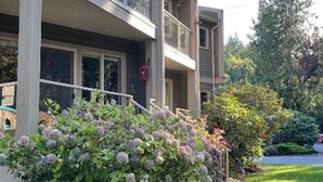 Un edificio de varios pisos con un balcón y un jardín bien cuidado al frente.