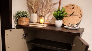 A wooden cabinet with a clock, a candle, and plants on top. - DOUTONBORI Sleeps up to 5 w 2 beds 1 sofa bed Convenient land (大阪市)