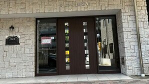 A building facade with a stone exterior, large glass doors, and a sign above the entrance. - DOUTONBORI Sleeps up to 5 w 2 beds 1 sofa bed Convenient land (大阪市)