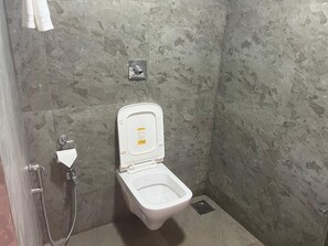 Un bagno piccolo e moderno con un water bianco, un soffione a mano e un rubinetto a parete.