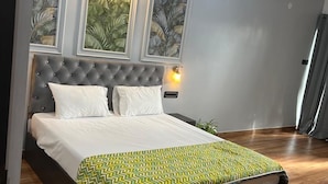 Una camera da letto con un letto, pavimento in legno e quadri appesi al muro.