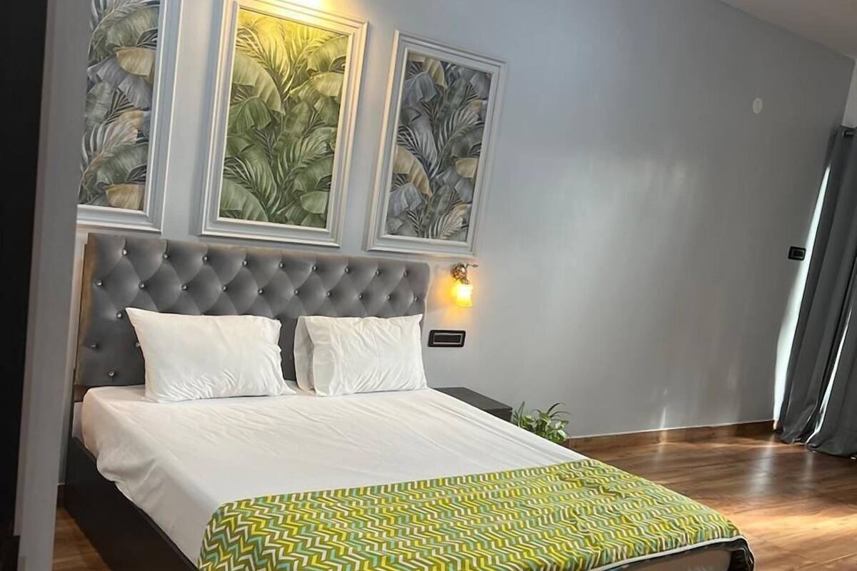 A bedroom with a bed, wooden flooring, and framed artwork on the wall.