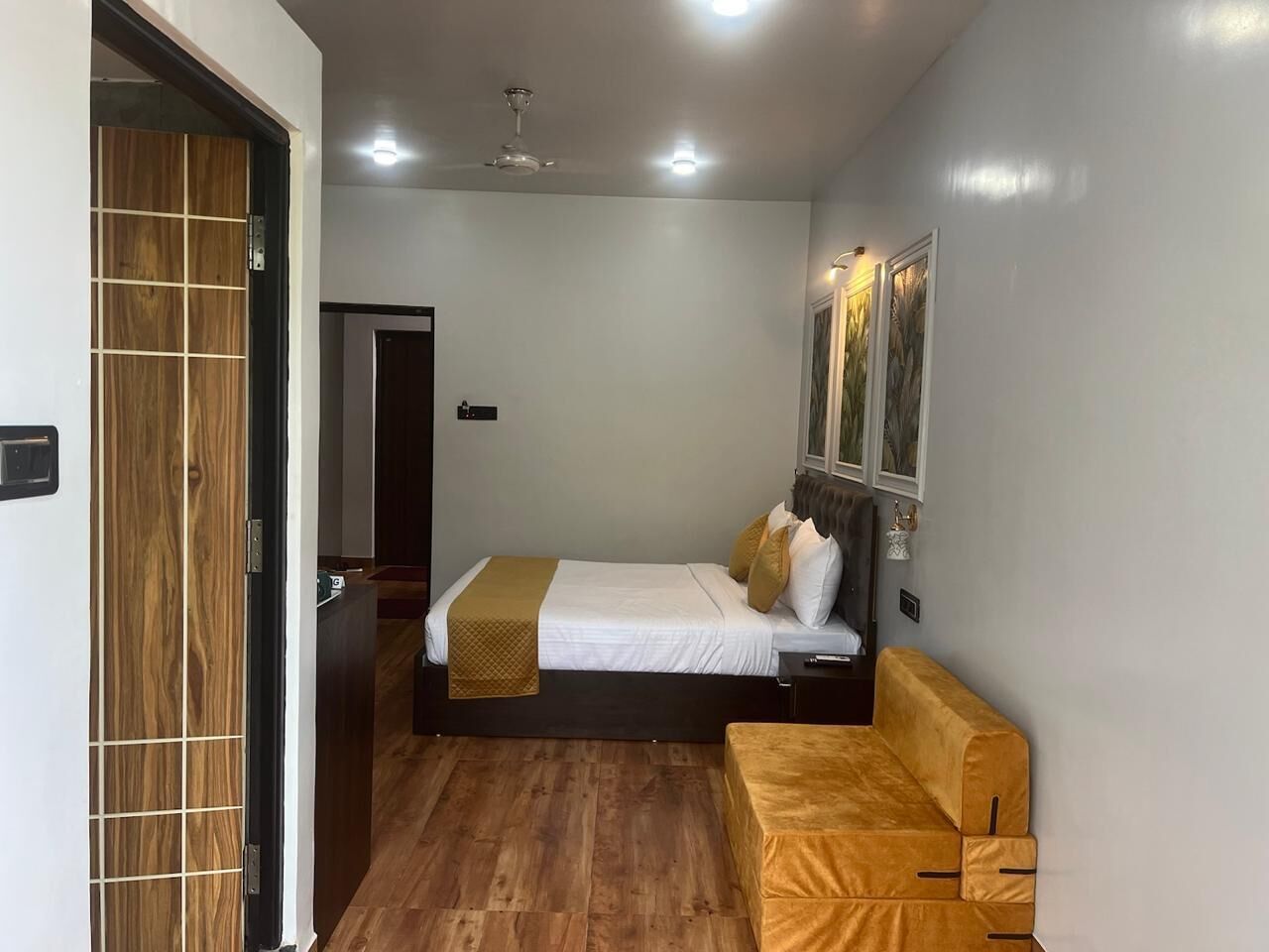A bedroom with a bed, a bedside table, a chair, a wooden wardrobe, and a ceiling fan.