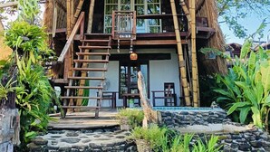Una casa tradizionale con tetto di paglia e una scala in legno che conduce a un balcone.