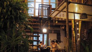 Un interno rustico in legno con zona pranzo, elementi in bambù e luci a sospensione.