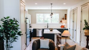 A modern kitchen with white cabinets, a central island, and a dining area with a lamp. - Upscale 2BR Apartment by MHM Luxury Properties (Athens)