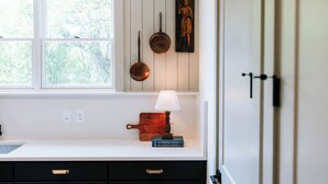 A kitchen with a window, a wooden cutting board, a lamp, and a painting on the wall. - Upscale 2BR Apartment by MHM Luxury Properties (Athens)