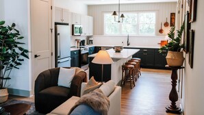 A modern kitchen with white cabinets, a central island, bar stools, and pendant lighting. - Upscale 2BR Apartment by MHM Luxury Properties (Athens)