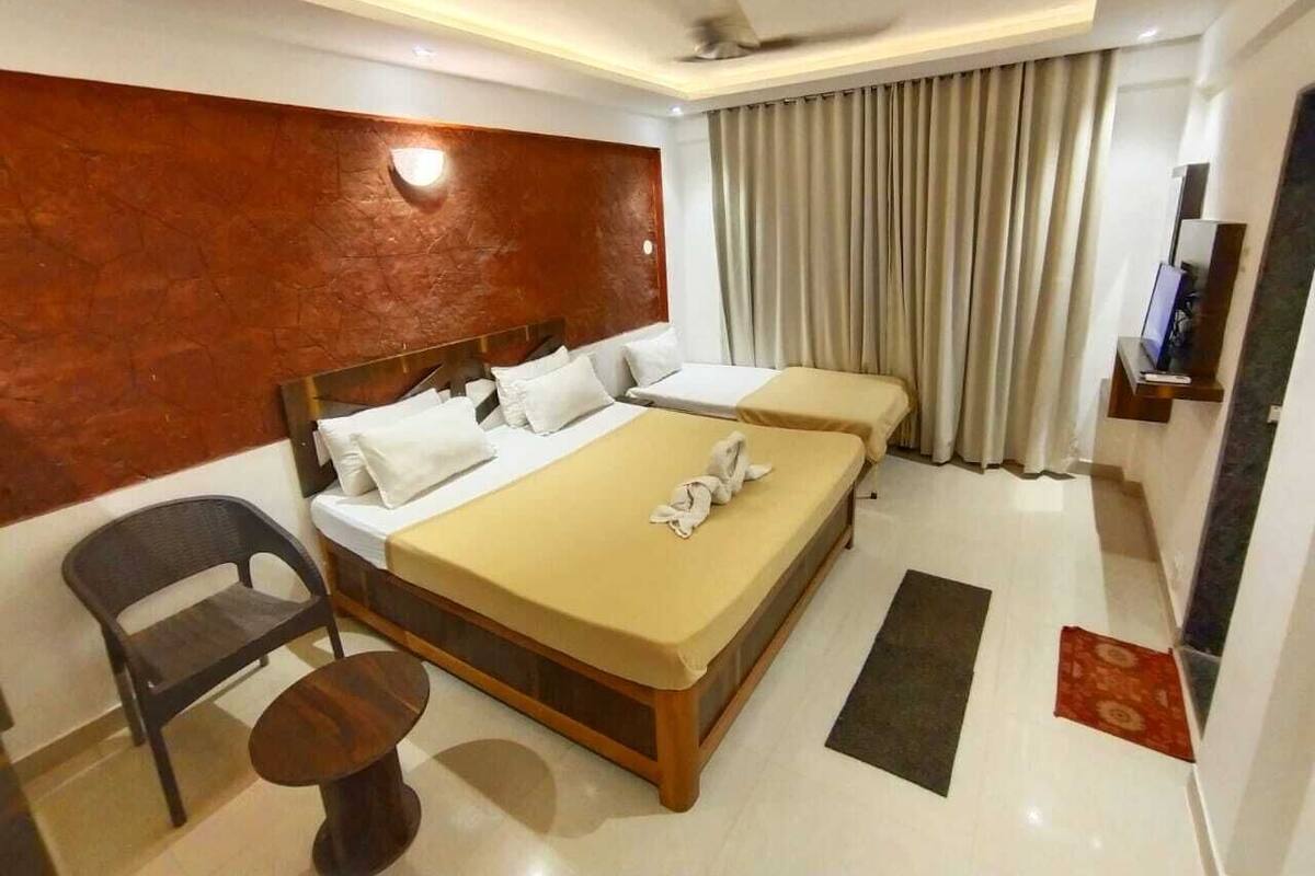 A hotel room with a large bed, a desk, a chair, and a TV.