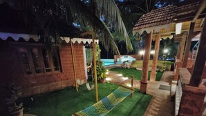 A well-lit outdoor area with a hammock, a small pool, and a brick structure. - Blue Sea Beach Resort (Malvan)