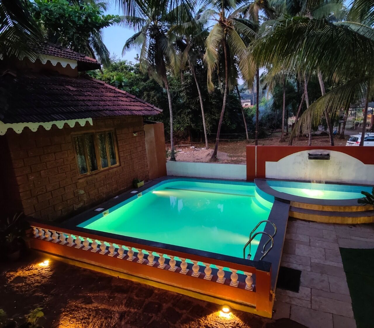 A swimming pool with a tiled deck, surrounded by palm trees and a brick building.