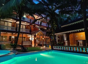 A hotel with a swimming pool, multiple balconies, and a well-lit outdoor area. - Blue Sea Beach Resort (Malvan)