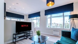 Ein modernes Wohnzimmer mit einem großen Flachbildfernseher, einem grünen Sofa und einem schwarzen Couchtisch.