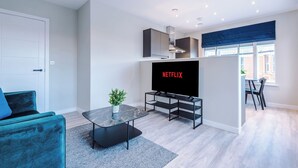 Ein modernes Wohnzimmer mit Fernseher, Sofa und Essbereich.