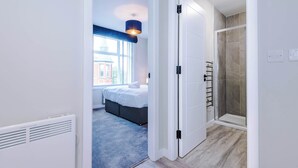 A modern bedroom with a large bed, a window, and a shower area.