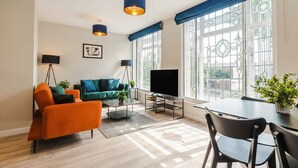 A modern living room with a sofa, coffee table, TV, and dining area.