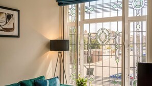 A room with a green sofa, a floor lamp, and a window with decorative glass panes.