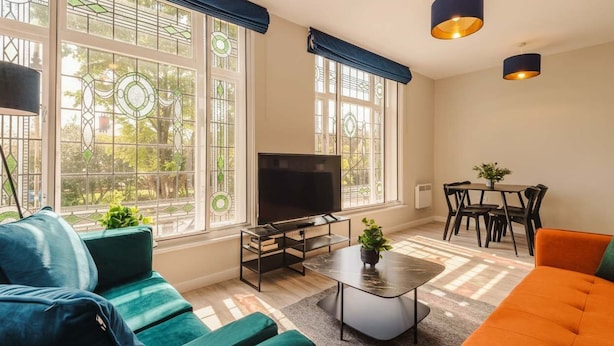 A modern living room with a TV, sofa, coffee table, and dining area.