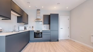 A modern kitchen with grey cabinetry, a built-in oven, and a microwave.