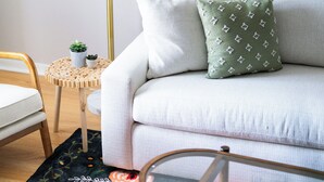 A modern living room with a sofa, a round coffee table, a floor lamp, and a small side table with plants.