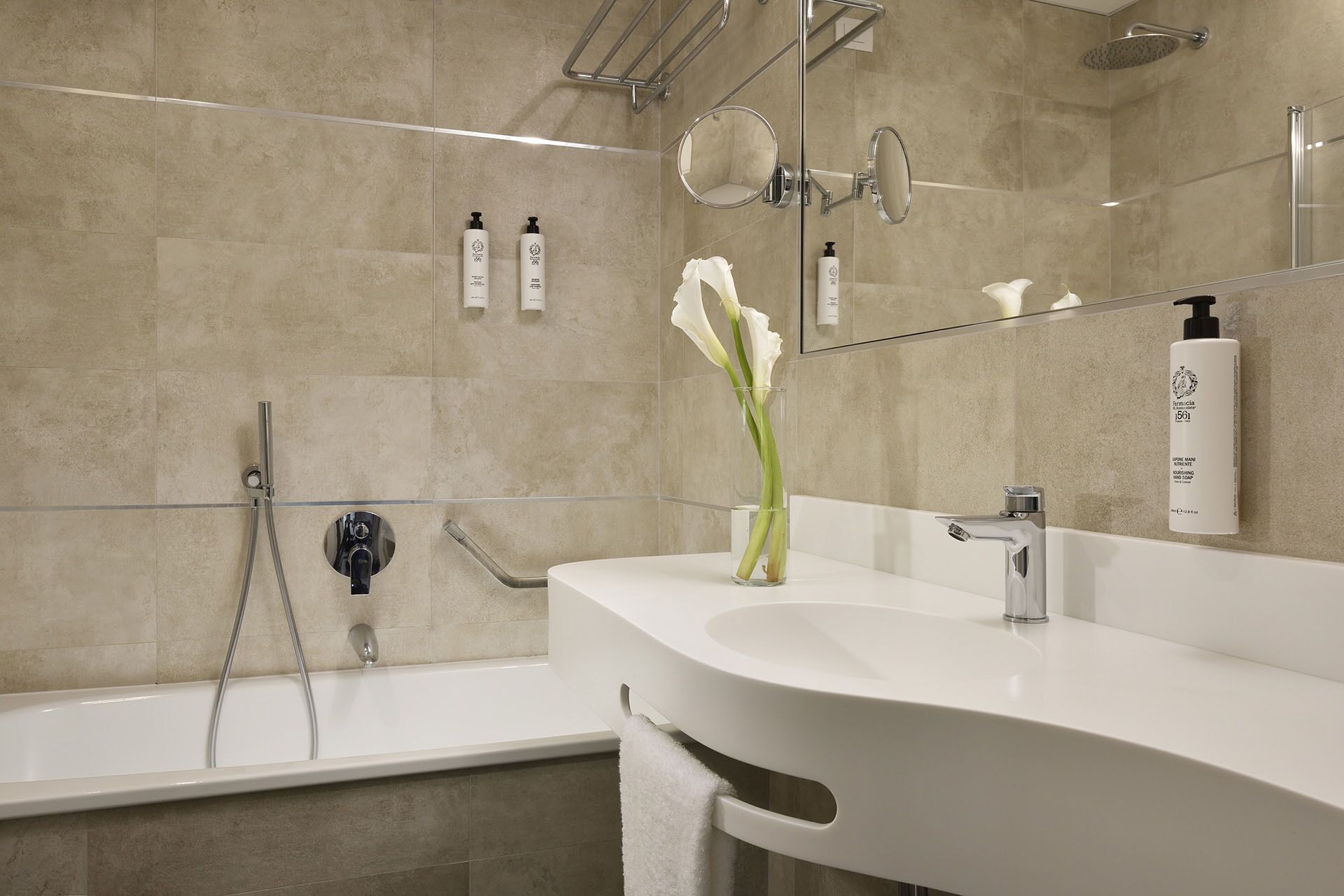 Un baño moderno con un lavamanos blanco, cabina de ducha con vidrio y un espejo grande.