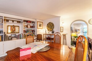 Ein Essbereich mit einem Holztisch, Stühlen und einem Bücherregal voller Bücher und Dekoration.
