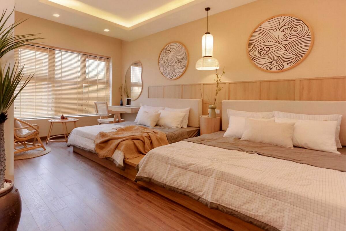 Un dormitorio con dos camas, una sala de estar con una silla, una mesita y una planta en maceta.
