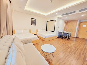 Une chambre d’hôtel avec deux lits simples, un canapé, une petite table ronde et un bureau avec des chaises.