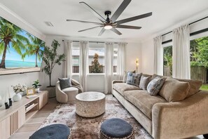 A living room with a sofa, armchair, round coffee table, and a ceiling fan.