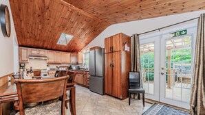 Une cuisine avec des meubles de rangement en bois, un réfrigérateur et un coin repas comprenant une table et des chaises.