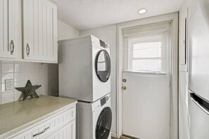 A compact laundry room with a washing machine, dryer, and a door with a window.
