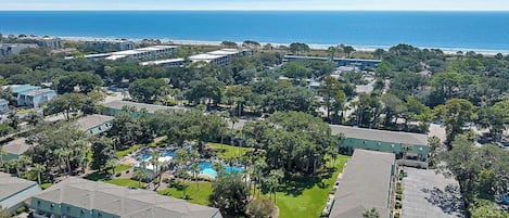 A coastal hotel with multiple buildings, a swimming pool, and a view of the ocean.