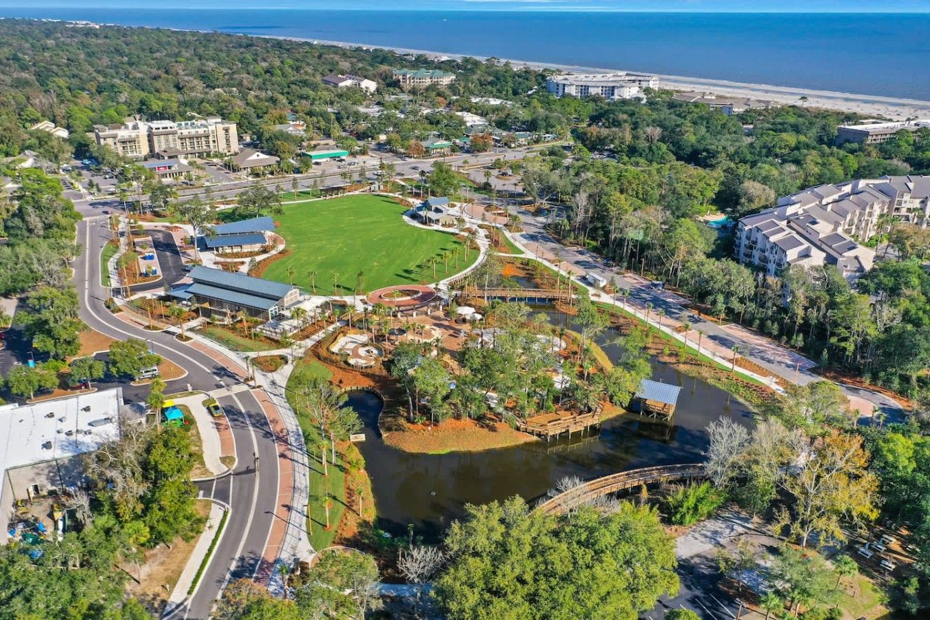 Luchtbeeld van een resort met een centraal waterpartij, aangesloten wegen en omliggende groen.