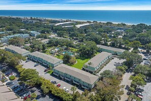 Vista aérea de un complejo hotelero con varias construcciones, zonas de estacionamiento y acceso directo a la playa.