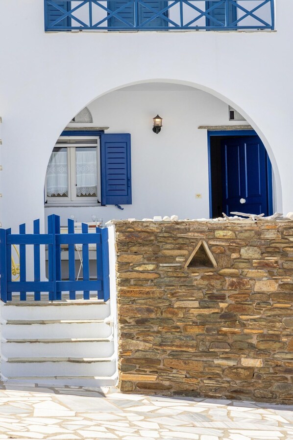 A white building with a stone wall and a blue gate.