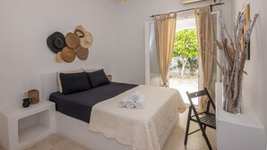 A neatly arranged bedroom with a bed, bedside tables, a hanging light fixture, and a view of the outdoors. - Cycladic Vibes Tinos (Tinos)
