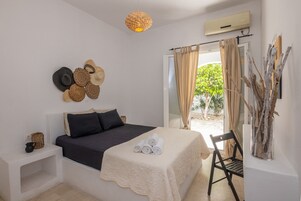 Un dormitorio ordenado con cama, mesitas de noche, una lámpara colgante y vistas al exterior.