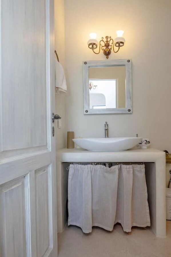 Une salle de bain avec un lavabo blanc, un miroir et un porte-serviettes.