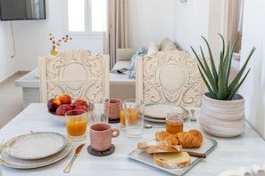 A breakfast table with plates, glasses, and pastries. - Summer Grace Tinos (Tinos)