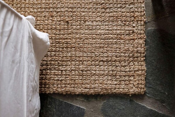 A textured woven mat on a stone surface, likely part of a room's decor or flooring. - Ballos for 6 in Exomvourgo (Tinos)
