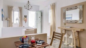 A cozy dining area with a wooden table set for two, a bowl of fruit, and a candle holder. - Ballos for 4 in Exomvourgo (Tinos)