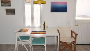 A dining area with a table, two chairs, a bottle, and two glasses. - Amberi Tinos in Panormos (Tinos)