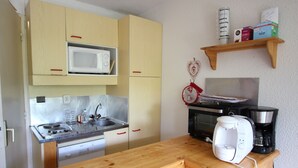A compact kitchen with a microwave, stove, and coffee maker. - Cozy studio with balcony and pets allowed in Chamrousse (Chamrousse)