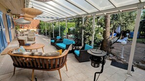 Ein Terrassenbereich im Freien mit Korbmöbeln, einem runden Tisch und einer Pergola.