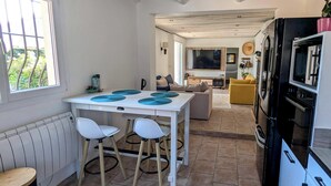 Een kleine keuken met een eethoek, een bank en een televisie in de woonkamer.