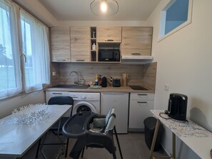 Compact kitchen with sink, dishwasher, coffee maker, washing machine, and dining area.